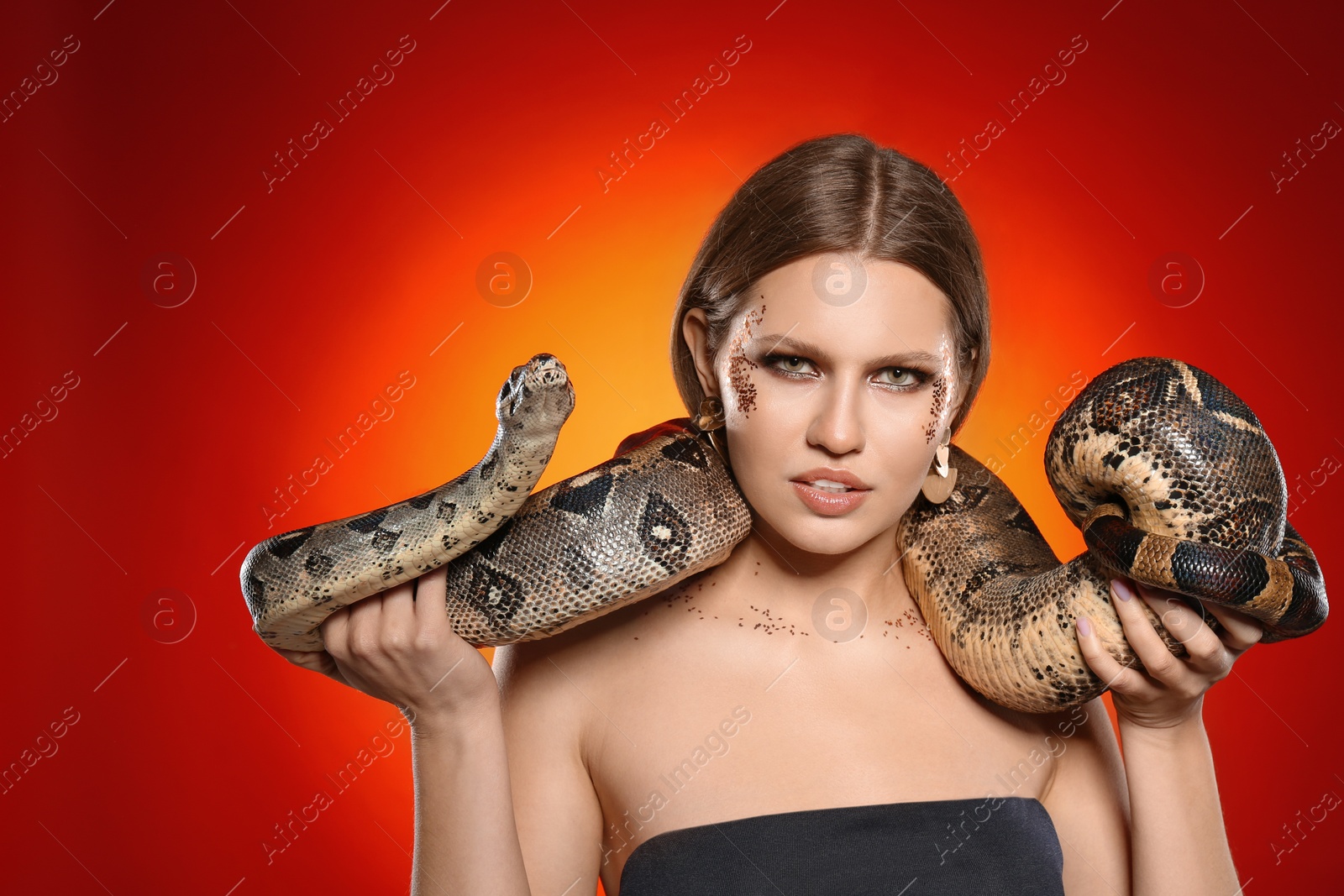 Photo of Beautiful woman with boa constrictor on bright colorful  background