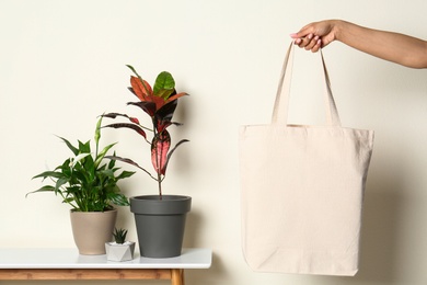 Woman with stylish blank eco bag against color background, closeup