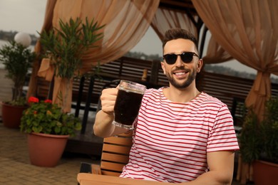 Photo of Man with glass of dark beer in outdoor cafe, space for text