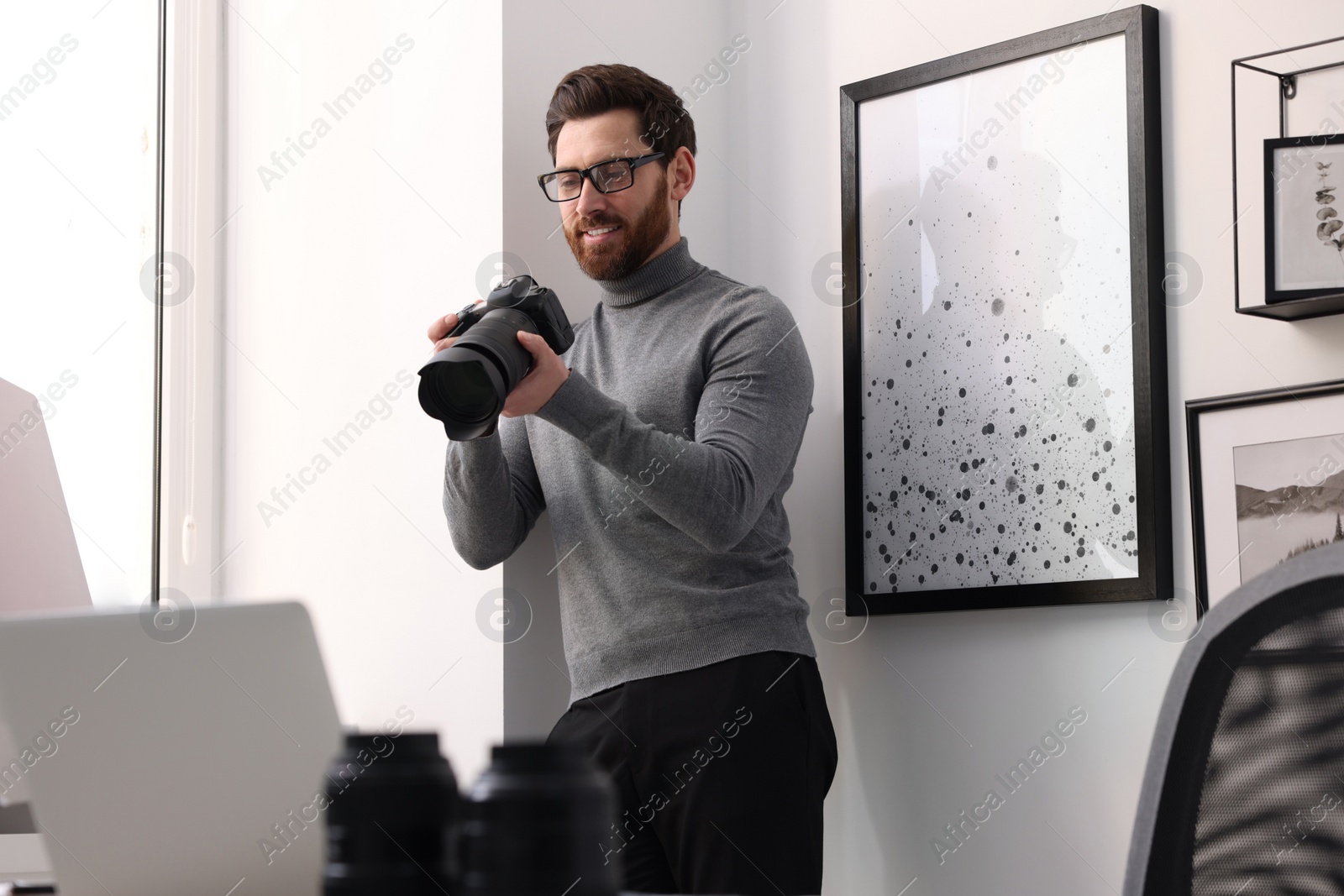 Photo of Professional photographer with digital camera near window indoors