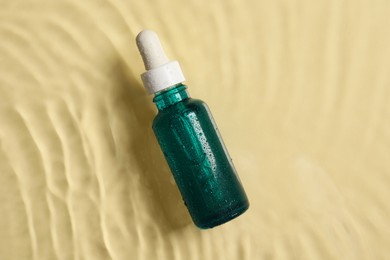 Bottle of cosmetic serum and water on beige background, top view