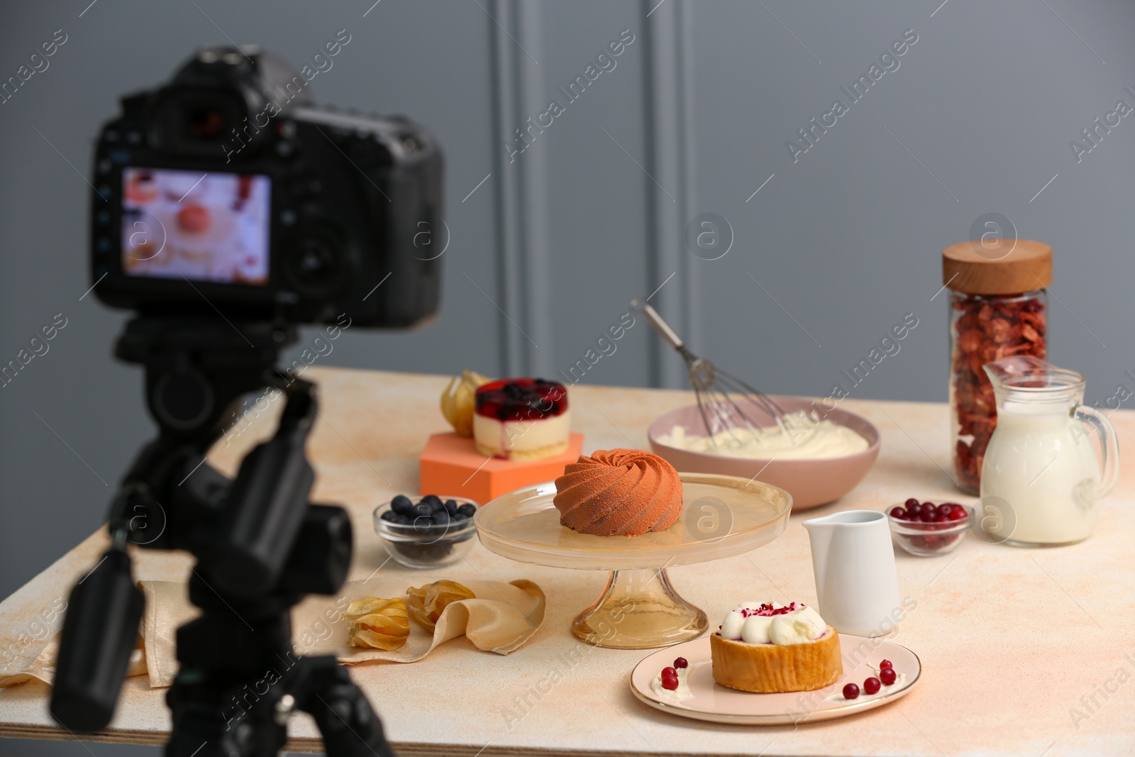 Photo of Professional camera and composition with delicious desserts on table in photo studio. Food photography