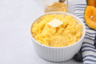 Photo of Tasty cornmeal with butter in bowl on table, closeup