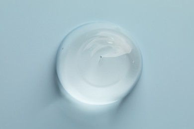 Sample of clear cosmetic gel on light blue background, top view