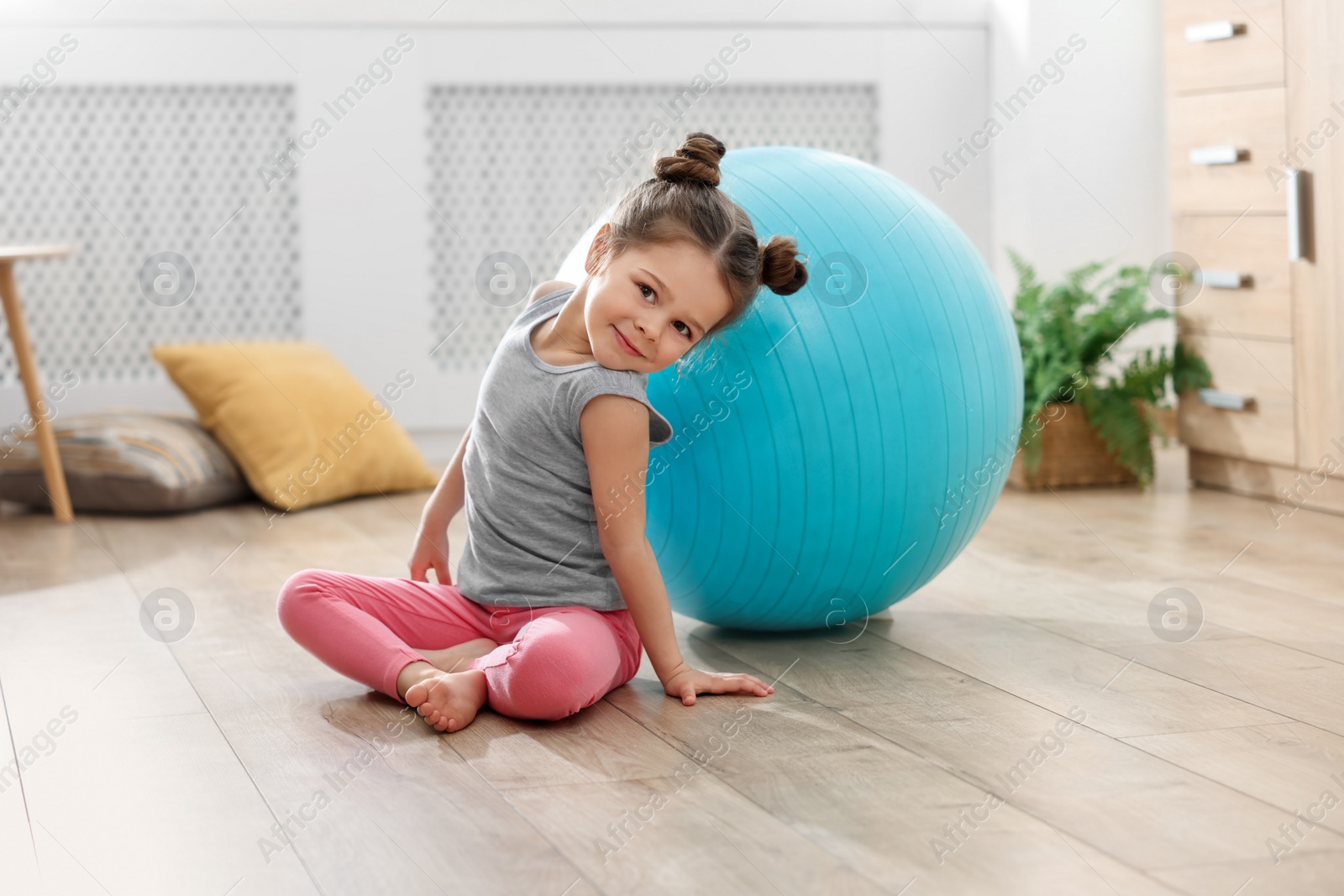 Photo of Little cute girl with fitness ball on floor at home. Doing exercises