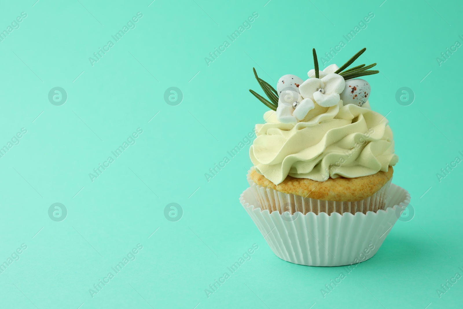 Photo of Tasty Easter cupcake with vanilla cream on turquoise background, space for text