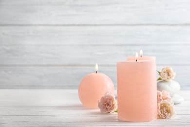 Photo of Burning candles, spa stones and flowers on table. Space for text