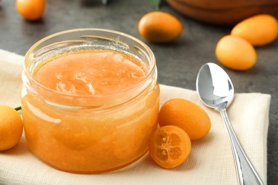 Delicious kumquat jam and fresh fruits on table, closeup