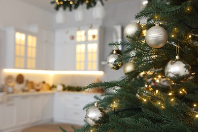 Closeup view of beautiful decorated Christmas tree in kitchen. Space for text