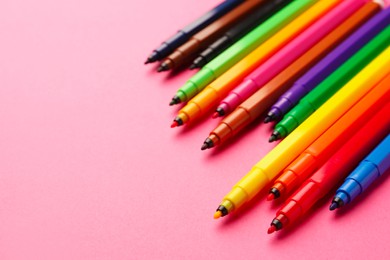 Photo of Many bright markers on pink background, closeup. Space for text