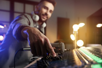Man working in modern radio studio, focus on professional mixing console