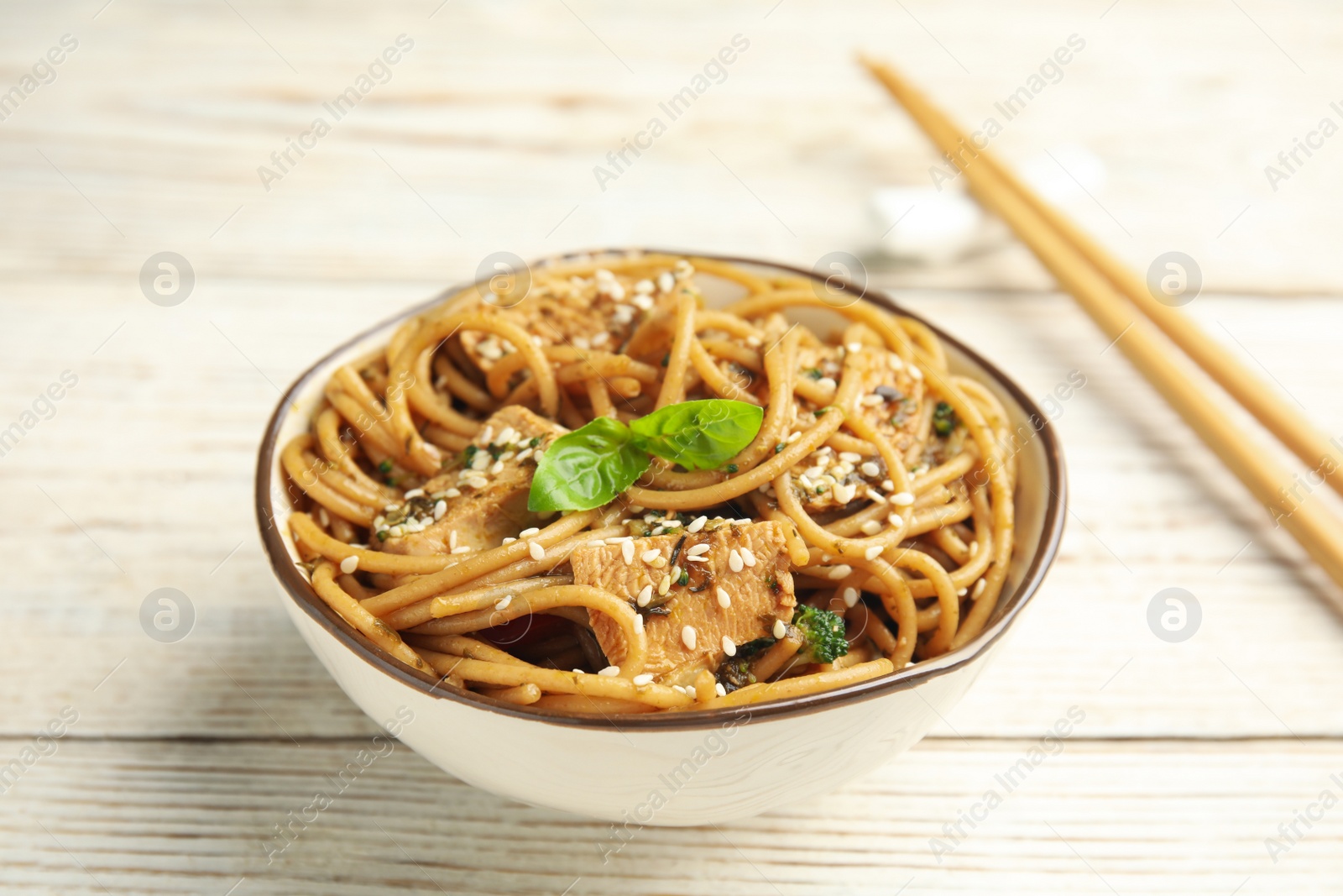 Photo of Tasty buckwheat noodles with meat in bowl on white wooden table