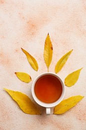 Photo of Autumn leaves and cup of tasty tea on color background, flat lay