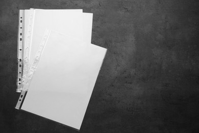 Photo of Punched pockets with paper sheets on grey background, flat lay. Space for text