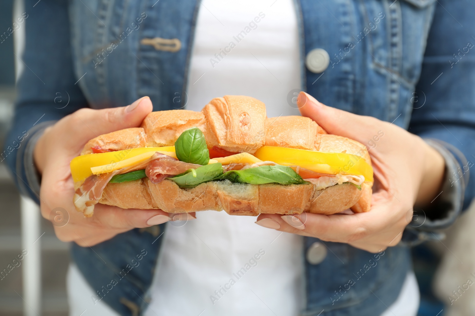 Photo of Woman holding tasty croissant sandwich, closeup