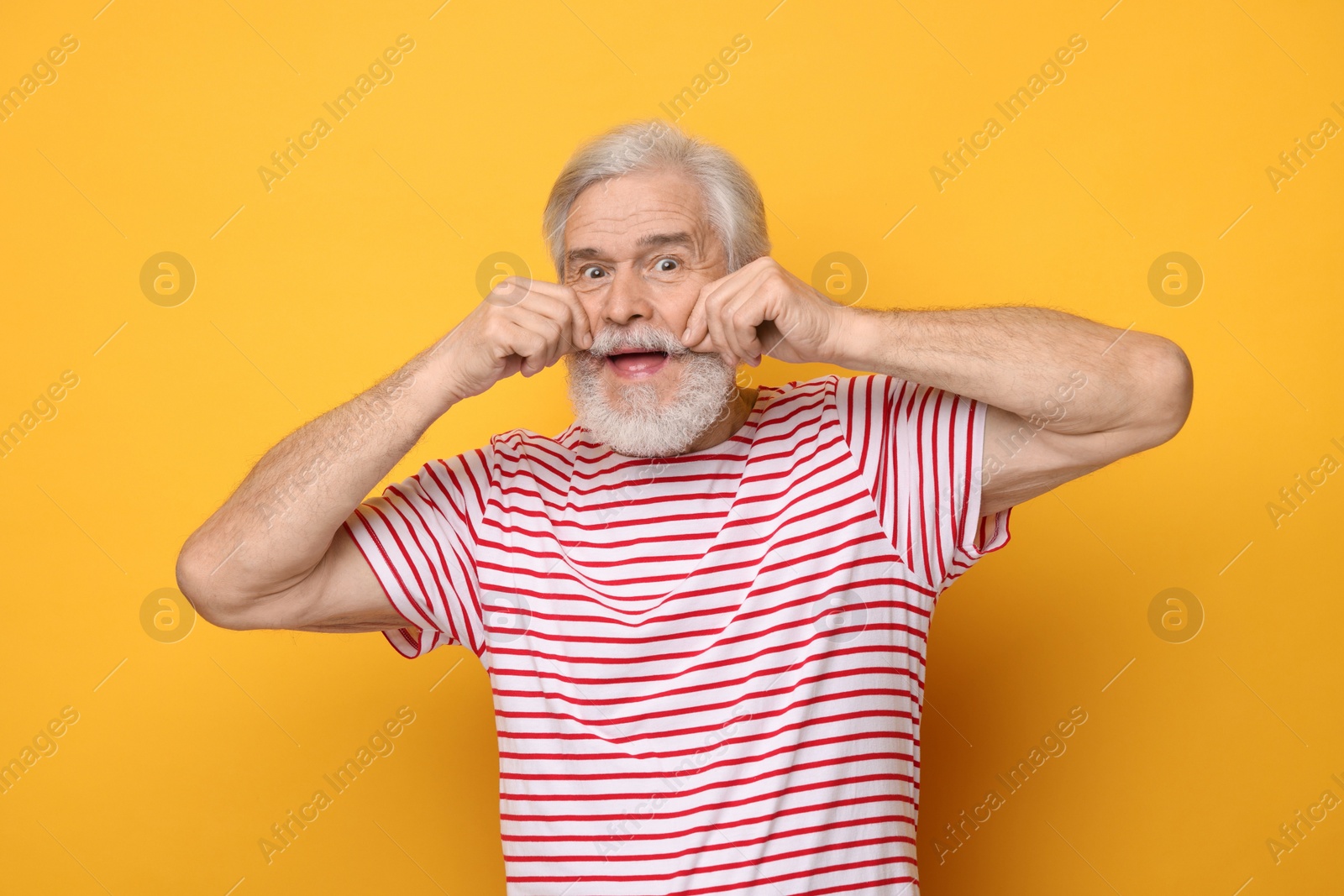 Photo of Senior man touching mustache on orange background