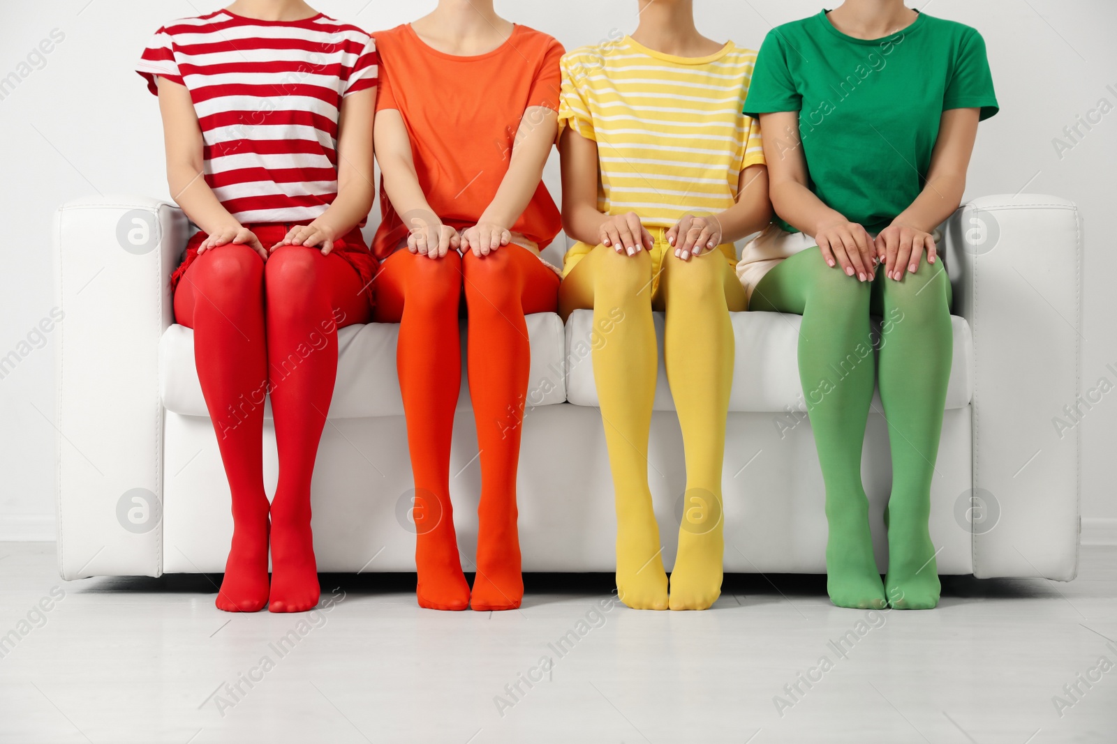 Photo of Women wearing bright tights sitting on sofa indoors, closeup