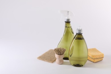 Bottles of cleaning product, brush and sponges on white background