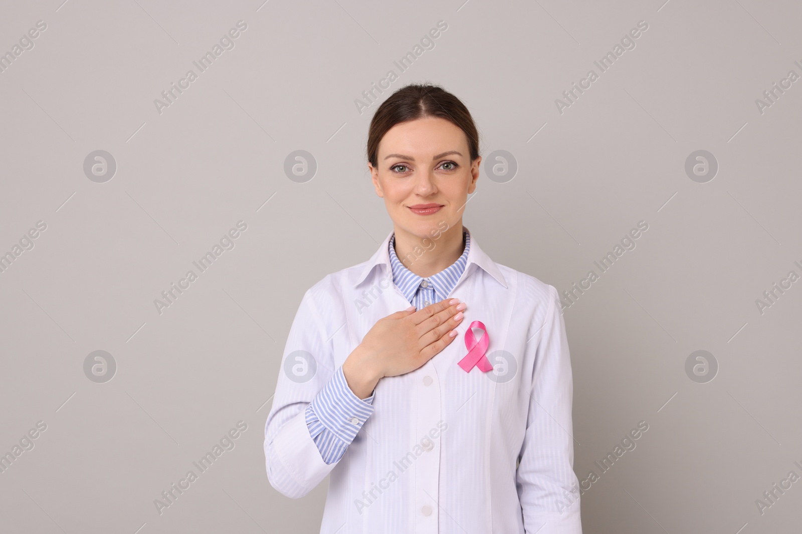 Photo of Mammologist with pink ribbon on grey background. Breast cancer awareness