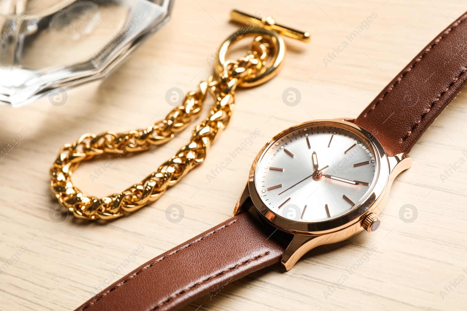 Photo of Luxury wrist watch and gold bracelet on wooden background, closeup