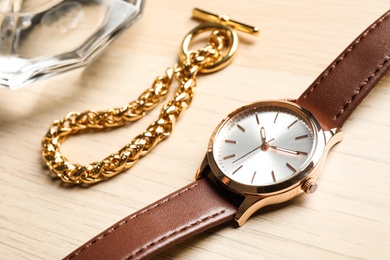 Photo of Luxury wrist watch and gold bracelet on wooden background, closeup
