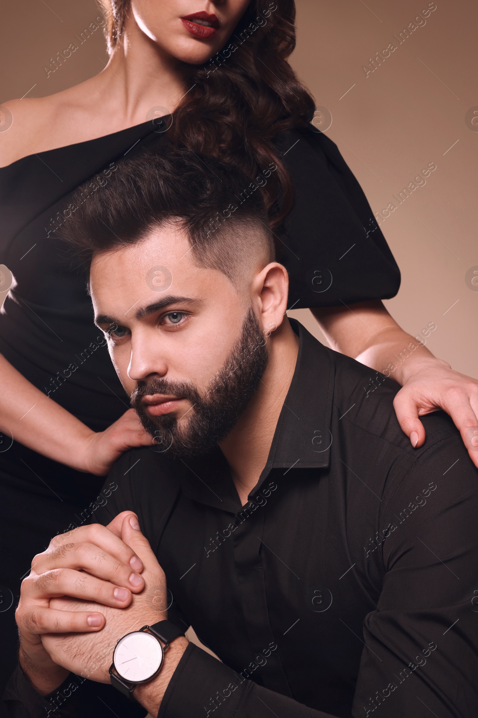 Photo of Handsome bearded man with sexy lady on light brown background