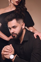 Photo of Handsome bearded man with sexy lady on light brown background