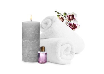 Image of Beautiful composition with rolled towels, orchid flowers and burning candle on white background. Spa therapy