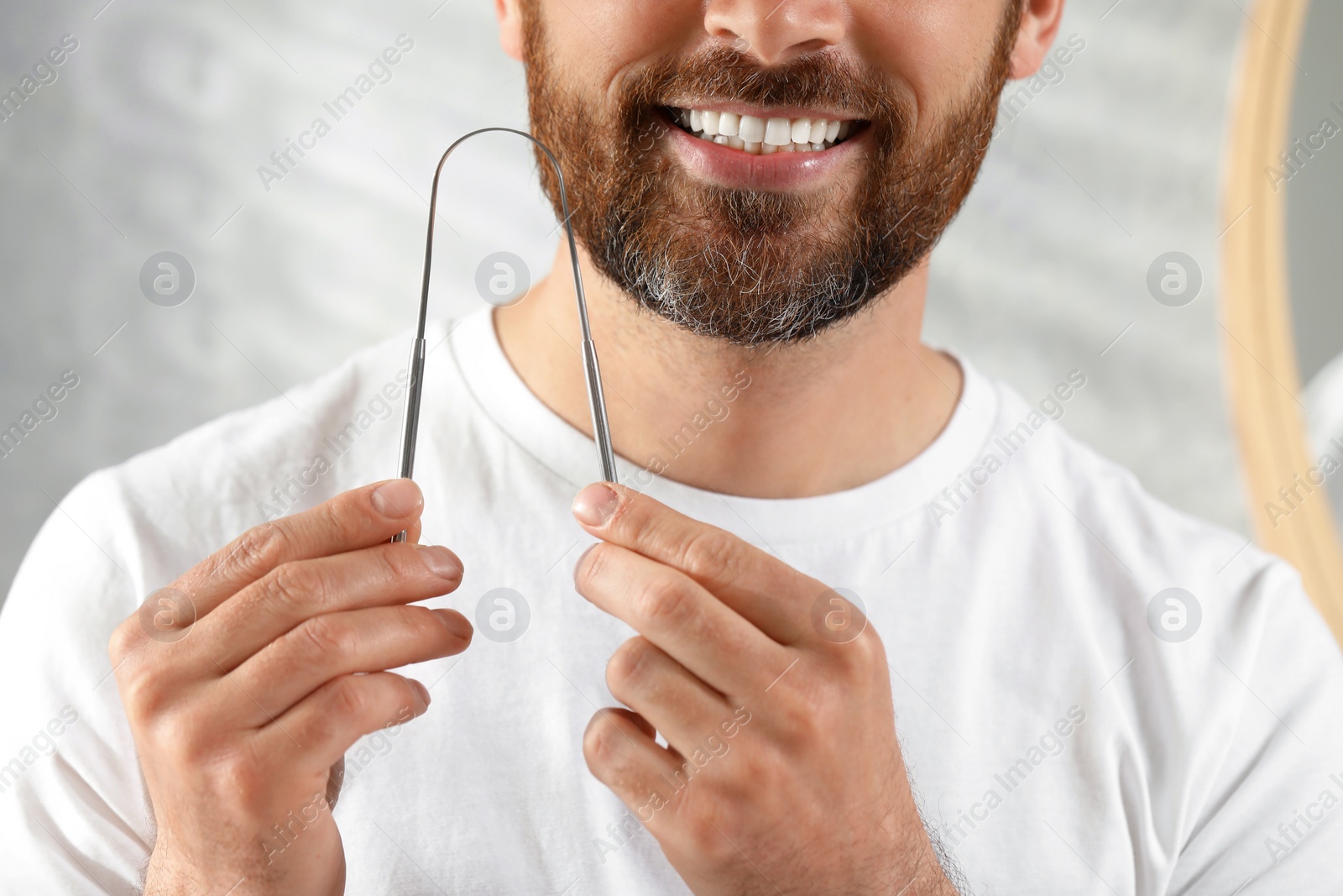 Photo of Man with tongue cleaner on blurred background, closeup