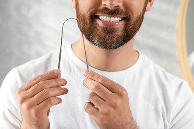 Photo of Man with tongue cleaner on blurred background, closeup