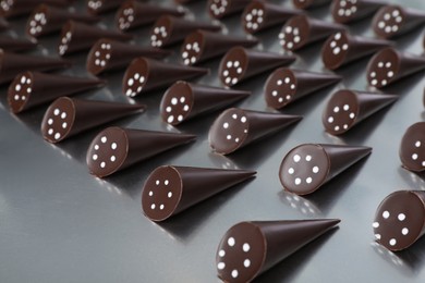 Photo of Many tasty chocolate candies on metal surface. Production line