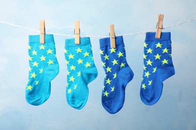 Cute child socks on laundry line against color background