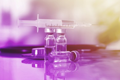 Image of Syringe, glass vials and stethoscope on mirror surface. Color toned