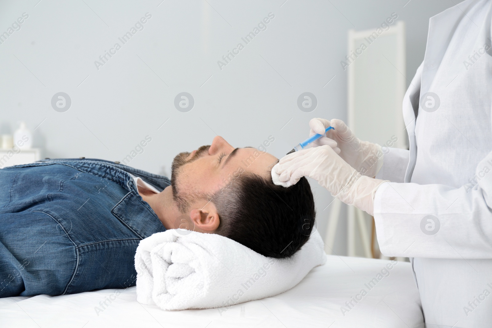 Photo of Man with hair loss problem receiving injection in salon