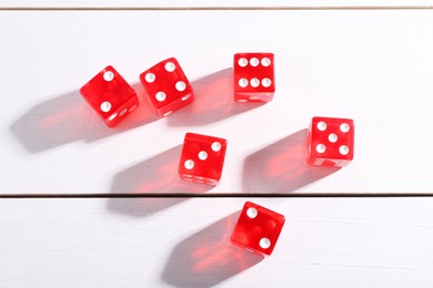 Photo of Many red game dices on white wooden table, flat lay
