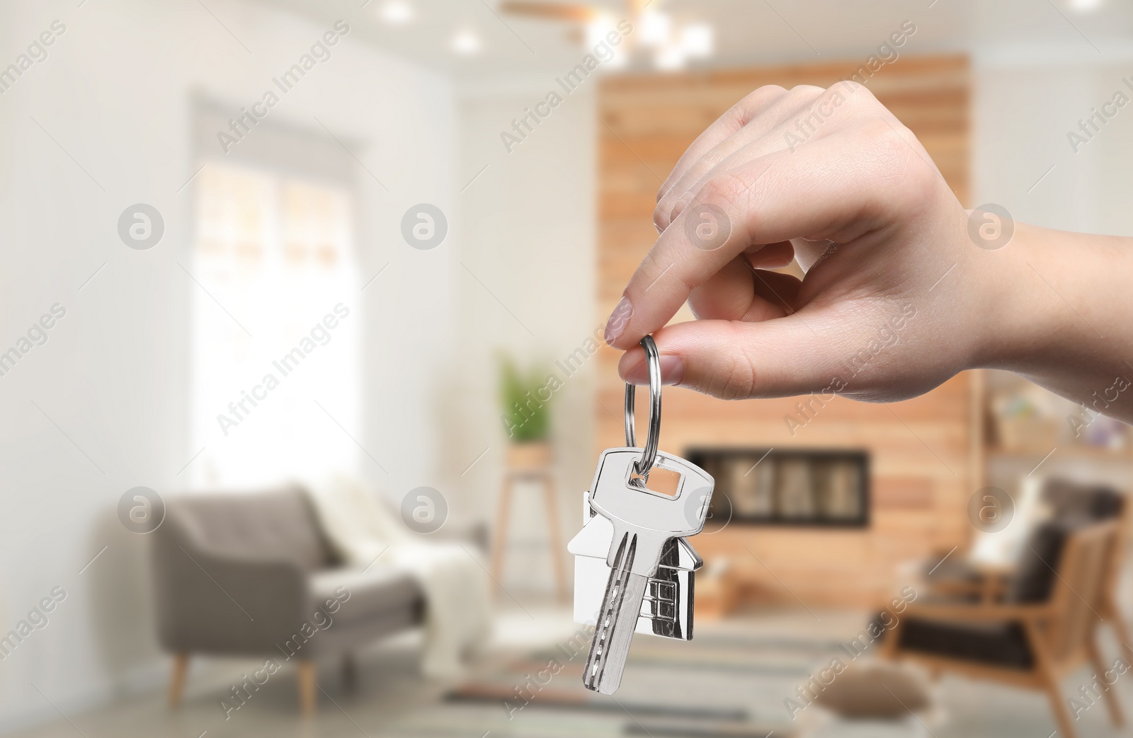 Image of Woman holding house key in room, closeup