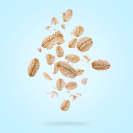 Image of Rolled oat flakes falling on light blue background