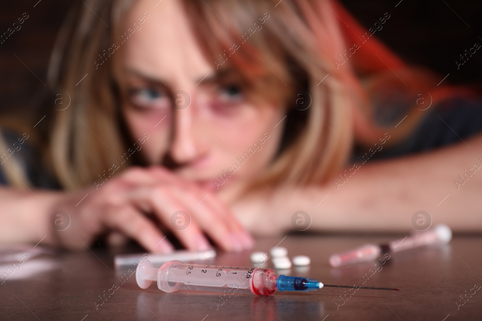 Photo of Addicted woman at table, focus on different drugs