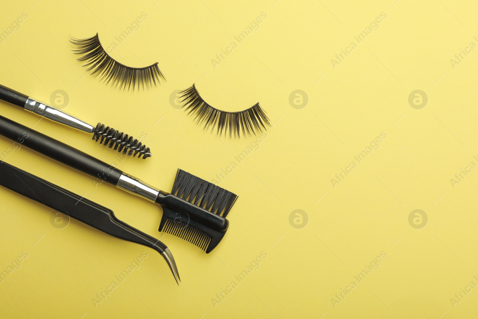 Photo of Flat lay composition of professional makeup tools and false eyelashes on color background, space for text