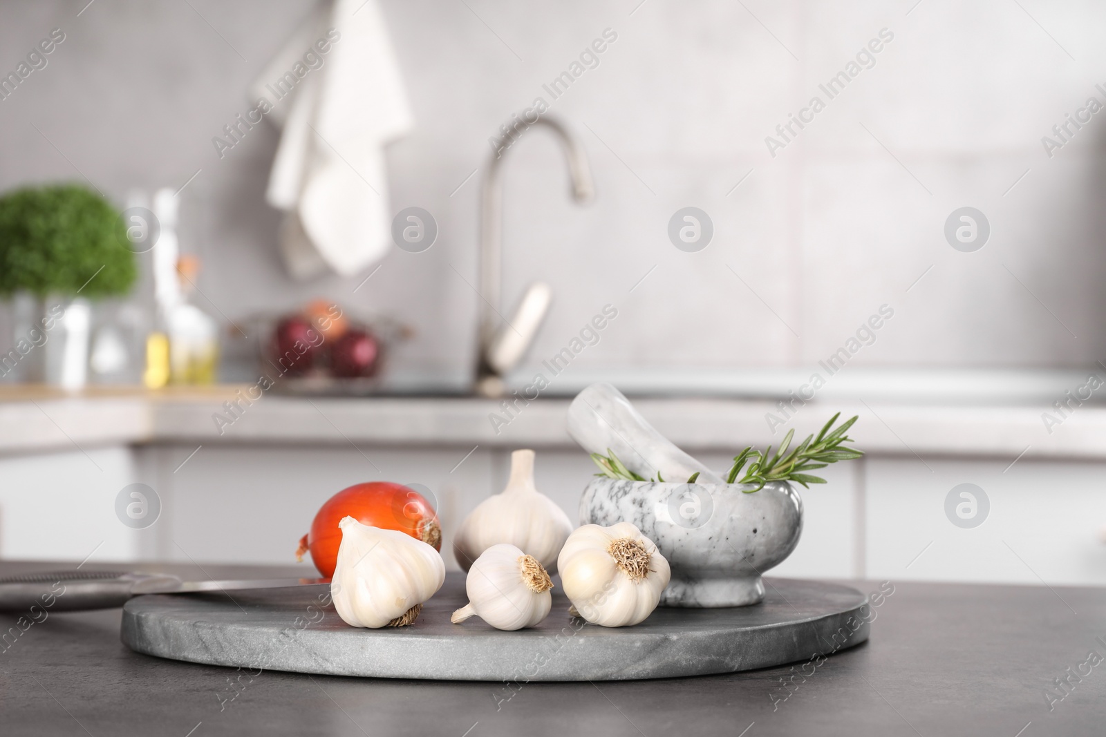 Photo of Fresh raw garlic, onion and rosemary on grey table