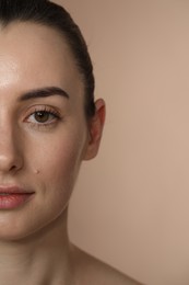 Beautiful young woman with healthy skin on light brown background, closeup