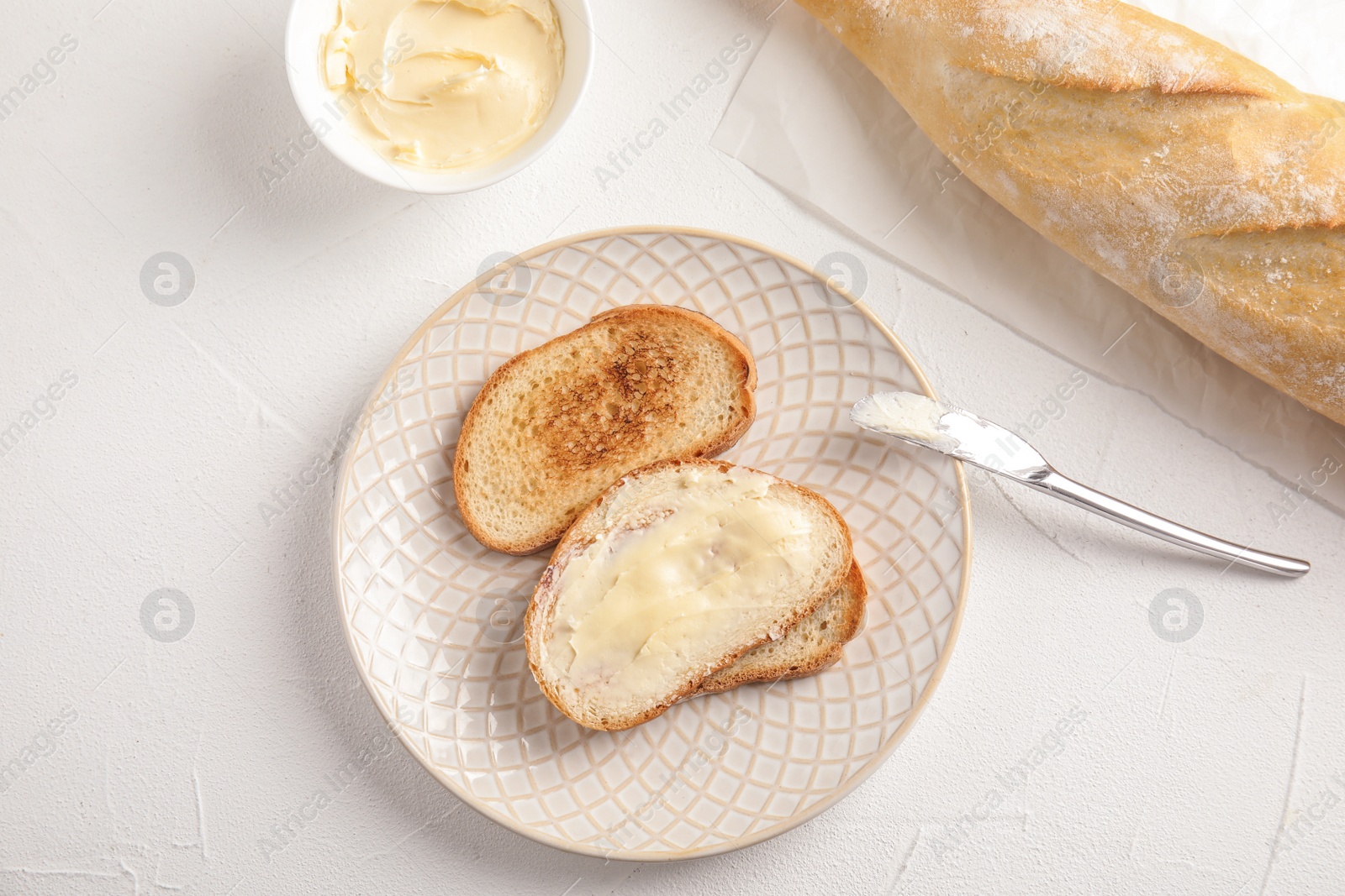 Photo of Tasty bread with butter served for breakfast on white table, top view