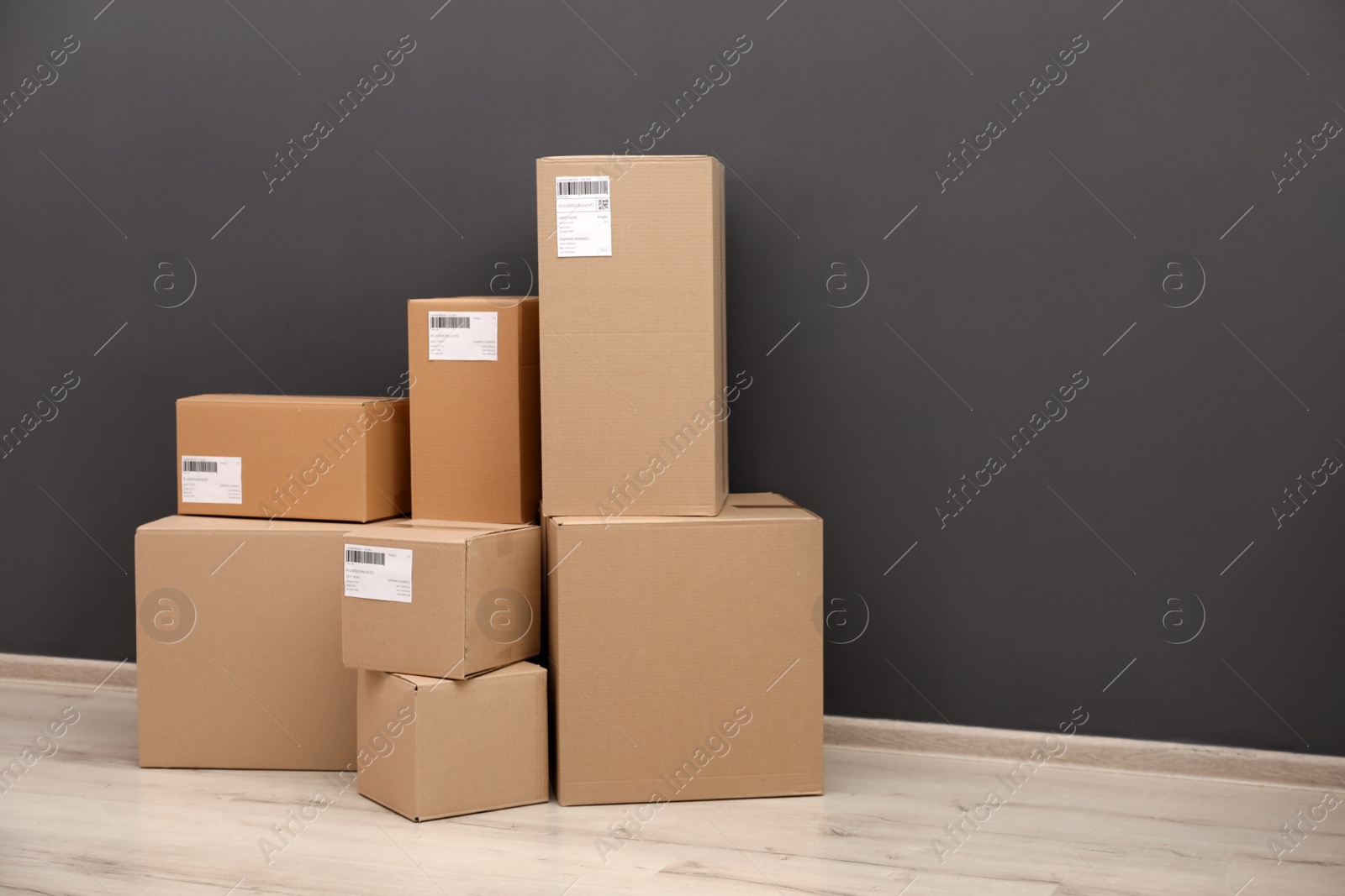 Photo of Stacked parcel boxes on floor against grey wall