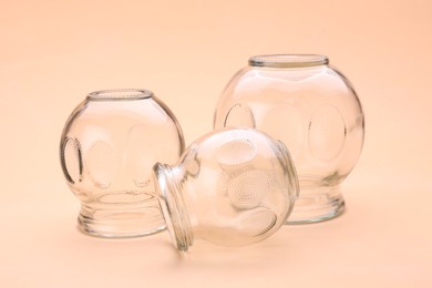 Photo of Glass cups on light coral background, closeup. Cupping therapy