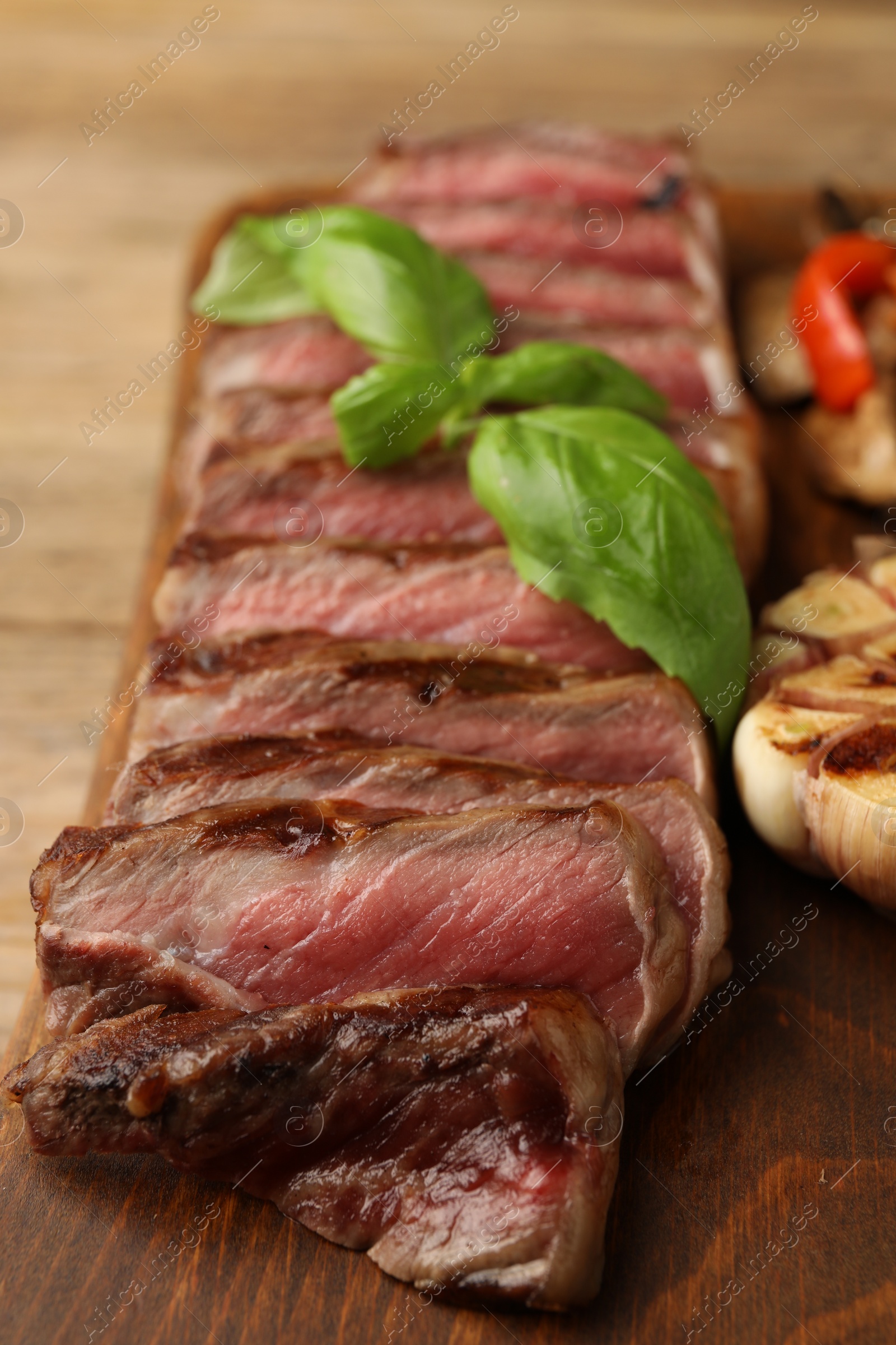 Photo of Delicious grilled beef steak with spices on wooden table, closeup