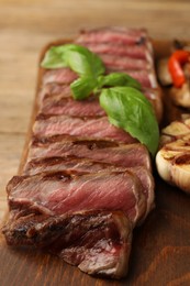 Photo of Delicious grilled beef steak with spices on wooden table, closeup