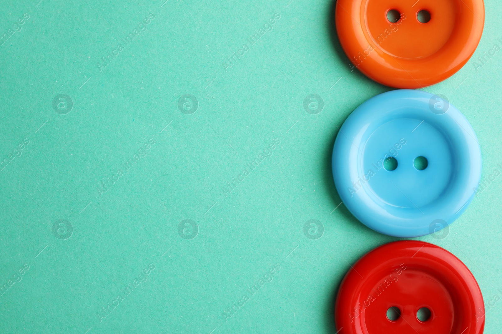 Photo of Many colorful sewing buttons on turquoise background, flat lay. Space for text