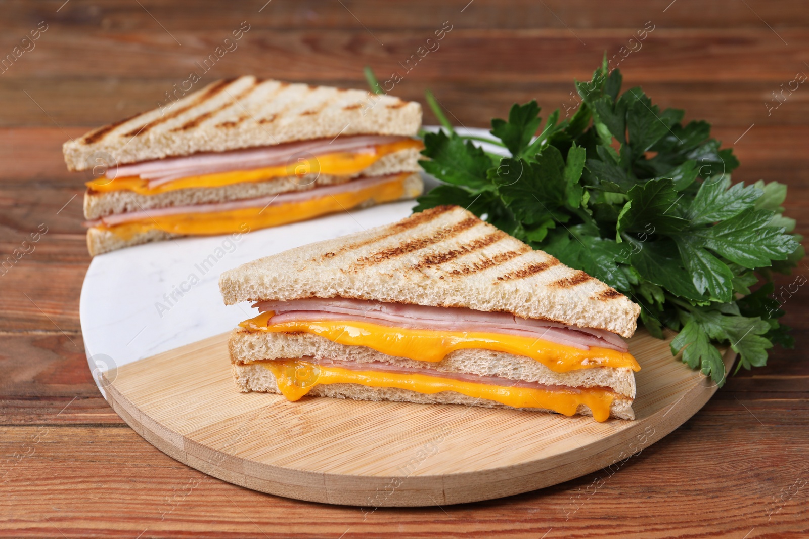 Delicious grilled sandwiches with ham, cheese and parsley on wooden table Photo of Delicious grilled sandwiches with ham, cheese and parsley on wooden table