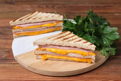 Photo of Delicious grilled sandwiches with ham, cheese and parsley on wooden table