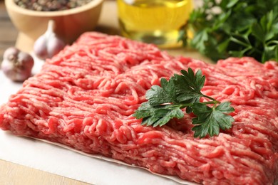 Photo of Raw ground meat and parsley on table, closeup